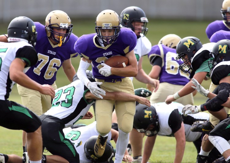 Nick Hutton of Cheverus tries to break a tackle by Massabesic's Ben Rohner during a Class A football game Saturday at Boulos Stadium. Cheverus won, 43-6.