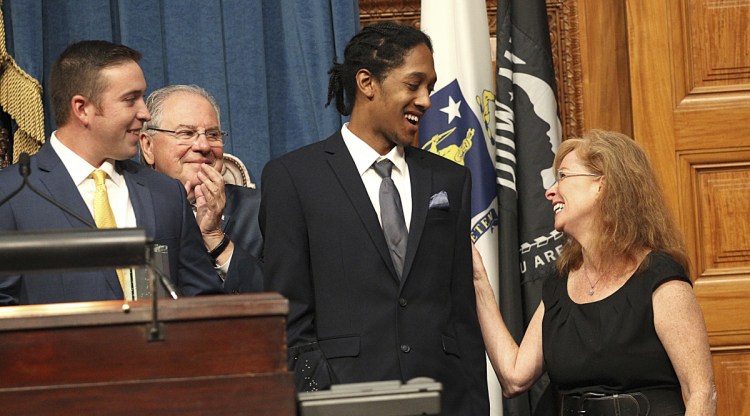 Rose Perkins, sister-in-law of Madeline Amy Sweeney, a flight attendant killed on 9/11, presents Ryan Saba, far left, and Ray Armstead, center, with a civilian bravery award Tuesday at a 9/11 remembrance ceremony at the State House in Boston.