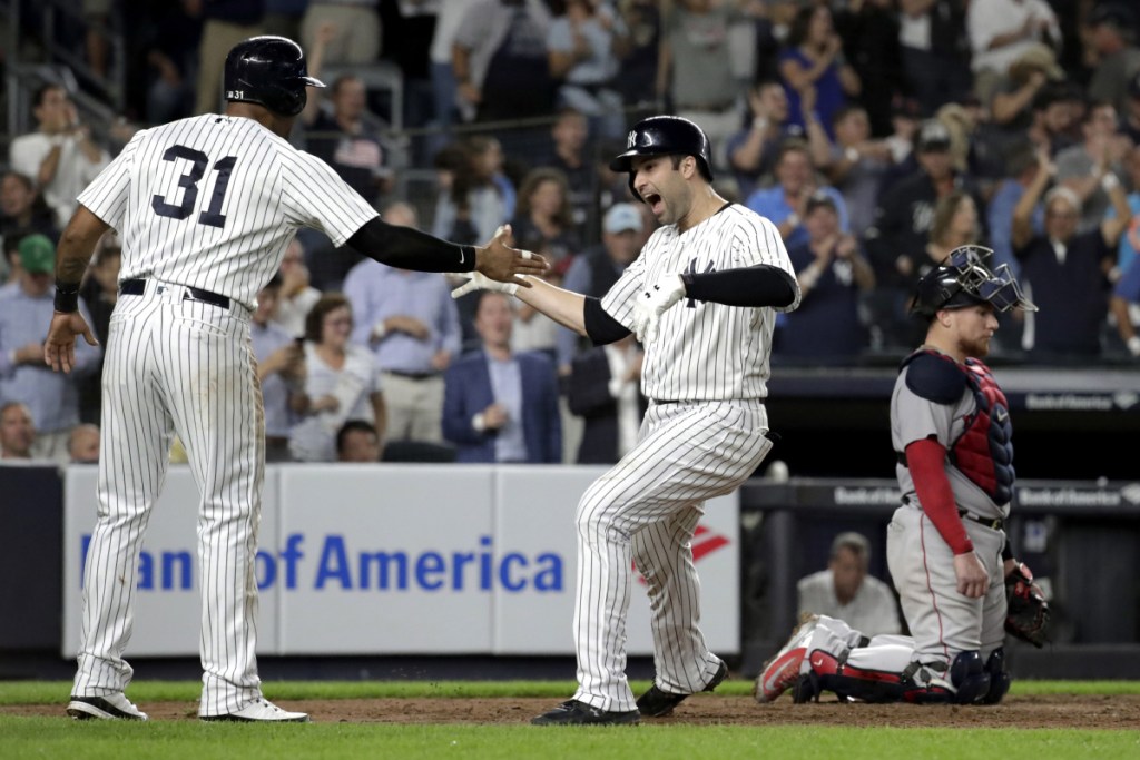 Red Sox catcher Christian Vazquez, right, kneels at the plate, Neil Walker, center, celebrates with Aaron Hicks after hitting a three-run home run off Boston pitcher Ryan Brasier that helped the Yankees beat the Red Sox and prevent Boston fron clinching its division title.