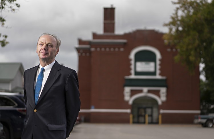 Alan Caron outside the former Notre Dame Catholic Church in Waterville, the city where he was born. The church excommunicated his mother when she had him out of wedlock. Caron retaliated when he was older, stealing priests' vestments from as many churches as he could find. The "political statement" was capped off by time in prison, where his affinity for bringing people together took root.