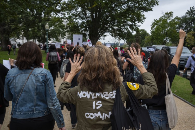 A woman marches past the Capitol to the National Mall to protest against the confirmation of then-Supreme Court nominee Brett Kavanaugh on the day of Christine Blasey Ford's hearing in Washington, D.C.