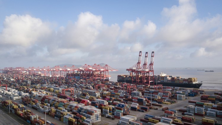 Containers sit stacked next to gantry cranes at the Yangshan Deep Water Port in Shanghai, China, on July 10, 2018.