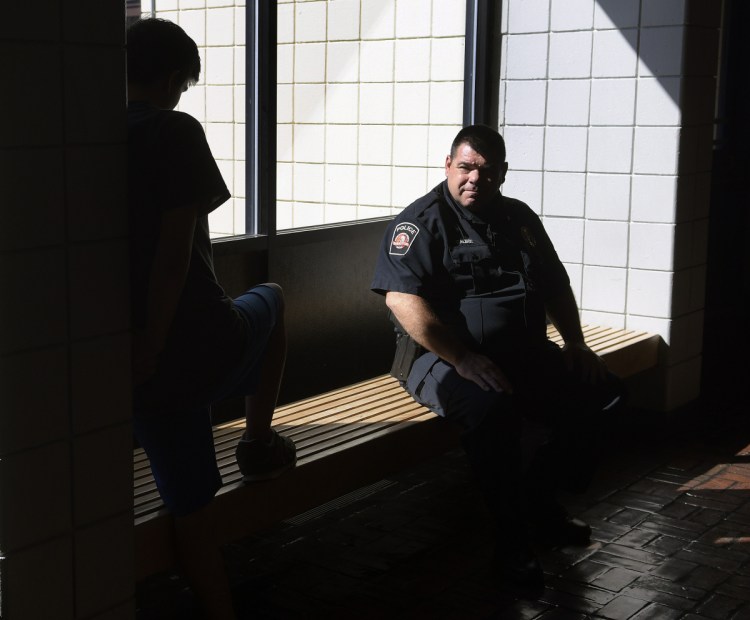 School resource officer John Dalbec talks with a student in the lobby Oct. 10 at Oak Hill High School in Wales.