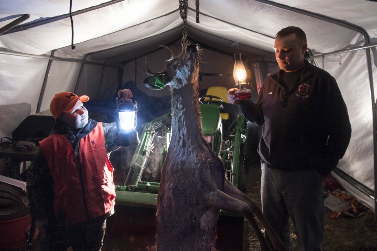 Chase Foss, 9, left, stands with the doe with antlers, a rare find, at his home in New Sharon on Tuesday night. Foss bagged the deer on his first day of hunting on Monday with his father, Daniel Foss, in Solon.