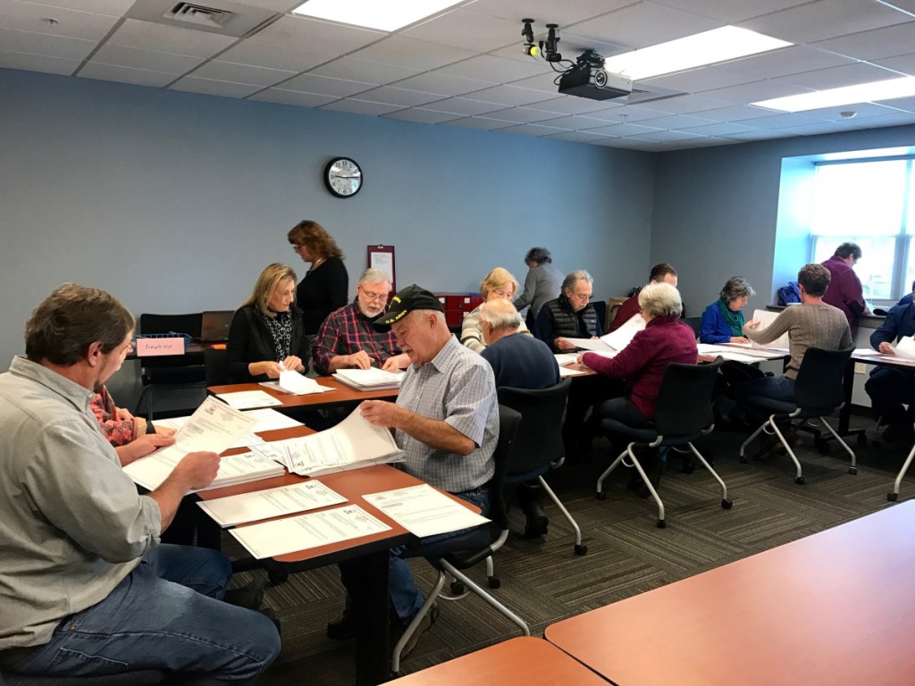 Election clerks and Waterville residents sort ballots from the Nov. 6 election on Nov. 10 at the Waterville police station as part of the process of recounting the votes of a referendum on banning plastic shopping bags from large stores.