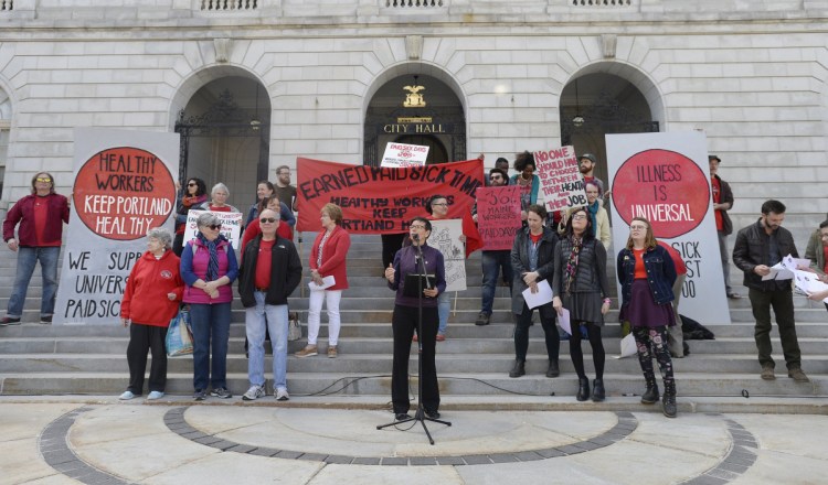 Eliza Townsend of the Maine Woman's Lobby speaks at a demonstration at Portland City Hall in April in favor of a proposed requirement for Portland businesses to provide all employees with one paid hour of sick leave for every 30 hours worked. A new proposal seeks paid sick leave for all Maine employees.