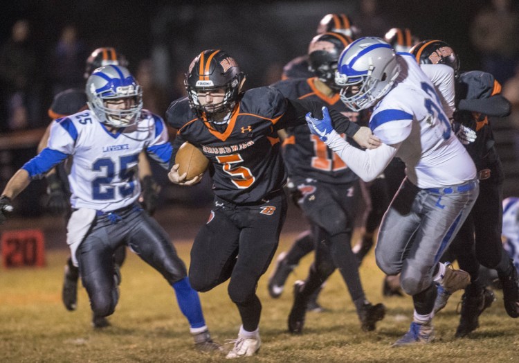 Brunswick's Nate Girardin spilts the Lawrence defense on a run up the middle during the Class B North championship game Friday night in Brunswick. Brunswick advanced to the state final with a 14-10 win.