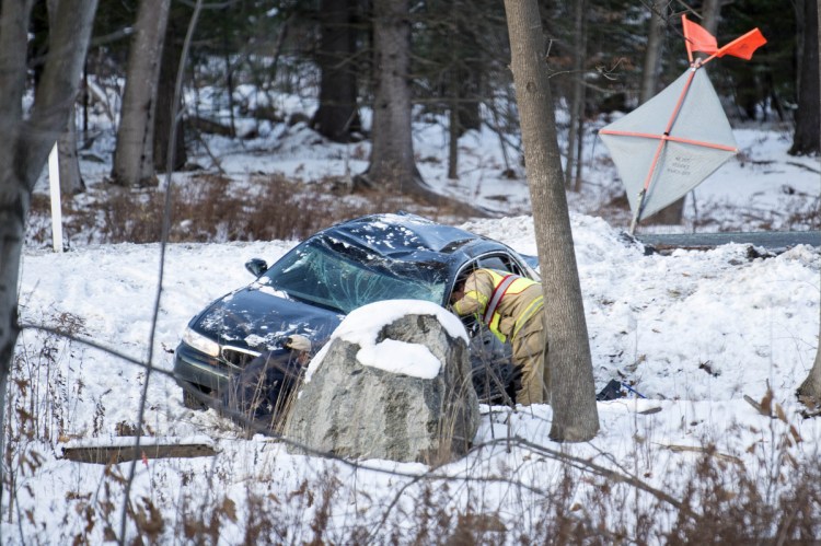 Lt. Scott Holst of the Waterville Fire Department inspects a car that went off the road Wednesday near mile marker 127 on Interstate 95 in Waterville. Staff file photo by Michael G. Seamans