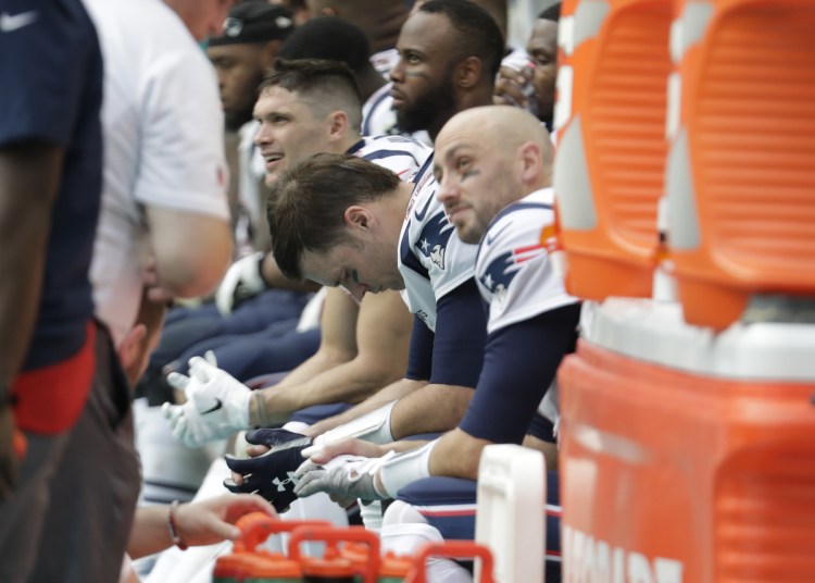 New England Patriots quarterback Tom Brady (12), center, looks down while on the sidelines, during the second half of an NFL football game , Sunday, Dec. 9, 2018, in Miami Gardens, Fla. The Dolphins defeated the Patriots 34-33. (AP Photo/Lynne Sladky)