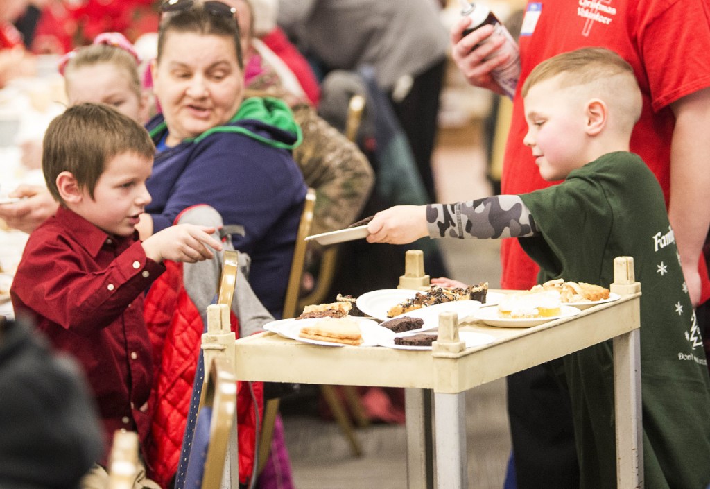 AT LEFT: Lucian Thomas Merrill, 6, right, the youngest volunteer, hands a piece of pie to Raiden Sidelinger, 6.