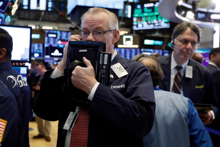 In this Thursday, Nov. 29, 2018, file photo trader Dennis Maguire, left, works on the floor of the New York Stock Exchange. 