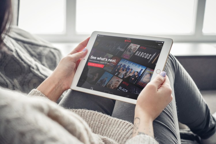 A traveler peruses the Netflix lineup on a tablet in an airport waiting area.