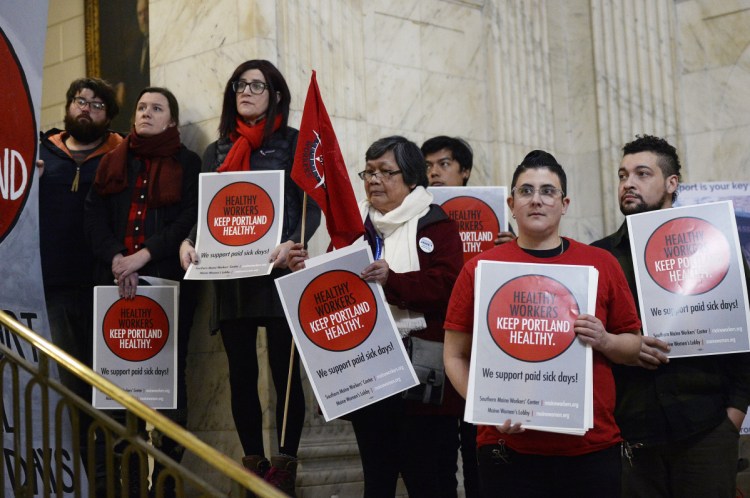 Supporters of paid sick leave for all workers in Portland hold signs during a press conference Tuesday at Portland City Hall.