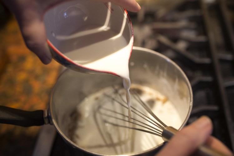 Christine Burns Rudalevige pours slightly sour milk into a pan with brown sugar and cornstarch to make butterscotch pudding.