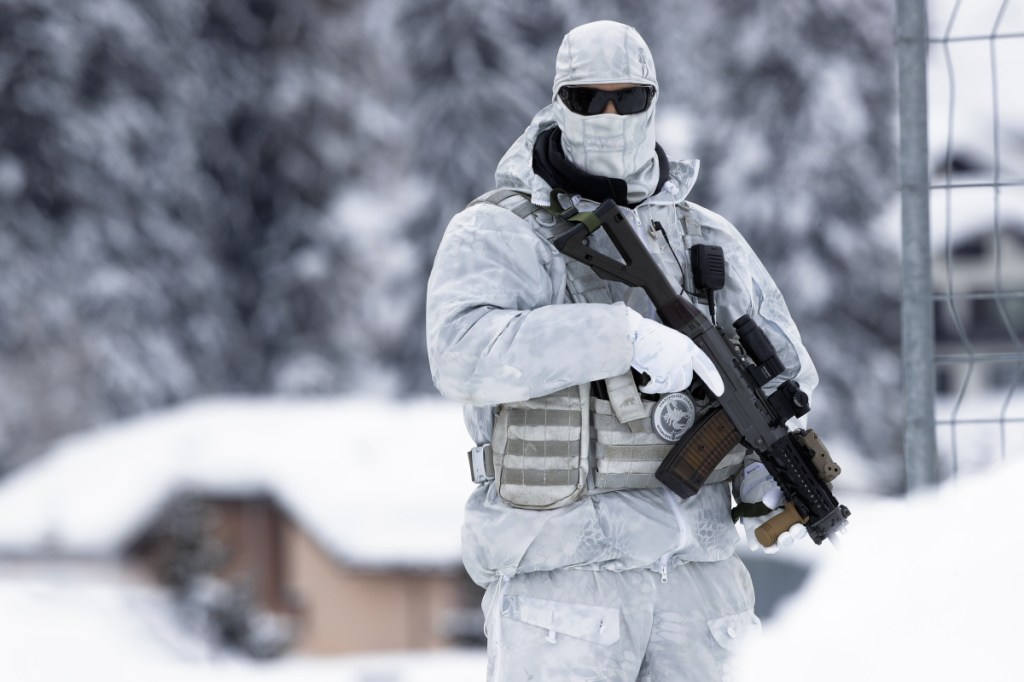 An armed Swiss police officer stands guard Monday on the roof of the center where the annual meeting of the World Economic Forum will take place in Davos, Switzerland.