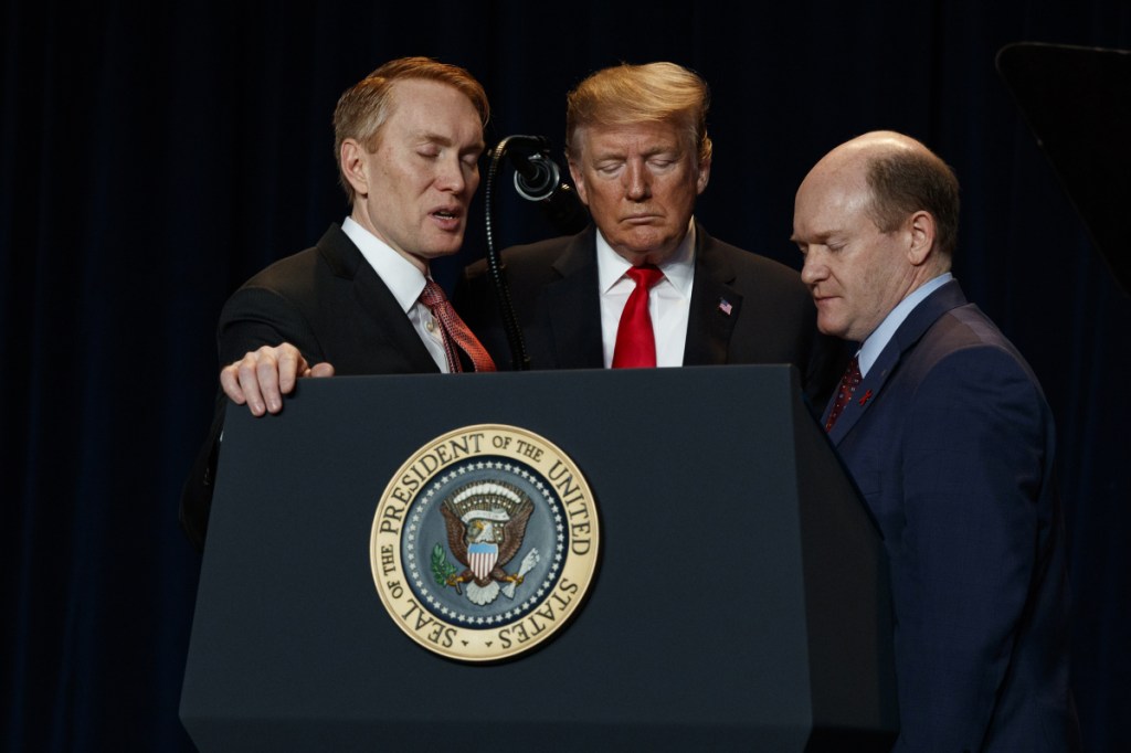 Rep. James Lankford, R-Okla., left, President Trump, center, and Sen. Chris Coons, D-Del., pray during the National Prayer Breakfast on Thursday in Washington. (AP Photo/ Evan Vucci)