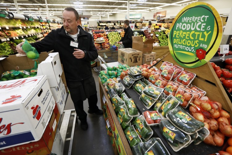 Assistant produce manager Dave Ruble stocks the imperfect produce section at the Hy-Vee grocery store in Urbandale, Iowa. After enjoying a brief spotlight in supermarket produce sections, blemished fruits and vegetables may already be getting tossed back in the trash.