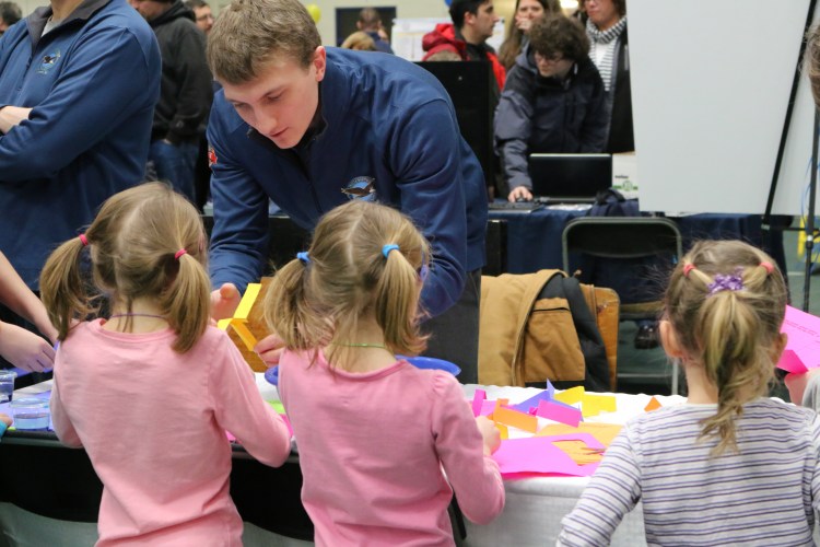 Nate Galle of Pratt & Whitney in North Berwick helps young visitors at the 2017 Engineers Week EXPO. 