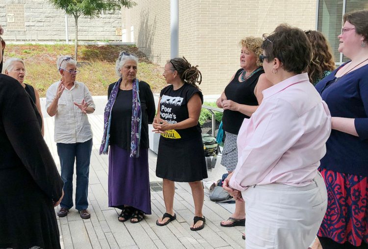 Defendants charged in May with criminal trespass at the Blaine House confer with each other and one of their attorneys after a hearing in August at the Capital Judicial Center.