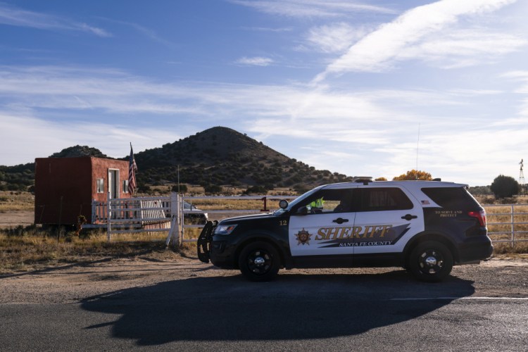 A Santa Fe County sheriff's deputy talks with a security guard briefly at the entrance to the Bonanza Creek Ranch in Santa Fe, N.M., on Monday. 