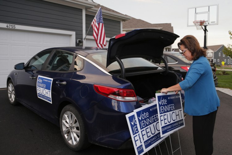 Jennifer Feucht, candidate for the Olentangy Local Board of Education, delivers campaign flyers and yard signs to Brad and Tina Krider on Thursday in Westerville, Ohio. Across Ohio and the nation, parental protests over social issues like mask mandates, gender-neutral bathrooms, teachings on racial history, sexuality and mental and emotional health are being leveraged into school board takeover campaigns.