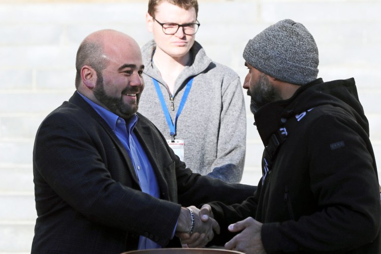 Brandon Mazer, left, shakes hands with opponent Roberto Rodriguez after Mazer won an at-large city council seat by drawing lots.