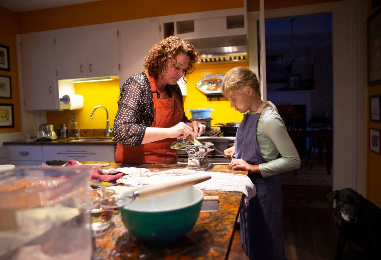 Maddie Brown, 11 of Brunswick, a fifth-grader at North Yarmouth Academy, helps Christine Burns Rudalevige make spinach and plain egg pasta dough using a hand crank pasta machine.