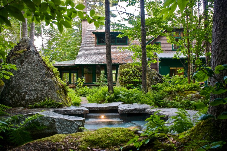 The hot tub and main home at "Floating Boulder," a 483 acre property in Orland, Maine. Other landscape highlights include a natural stone swimming pier and outdoor shower built into granite walls.