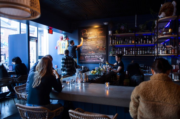 Server Paul Bryant adjusts the menu board at Paper Tiger restaurant and bar. 